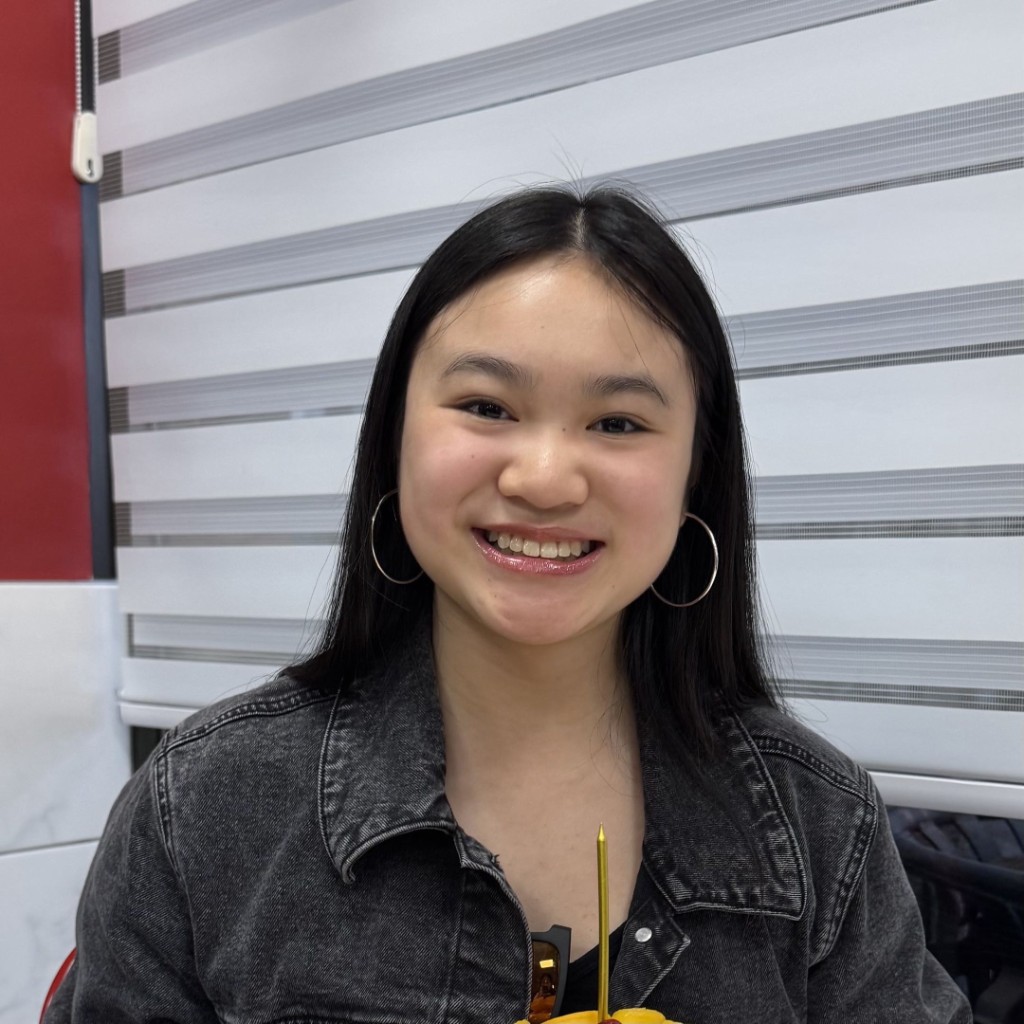 Portrait of Carinna Lee, HackBU Vice President of Outreach, smiling in a gray denim jacket and hoop earrings.