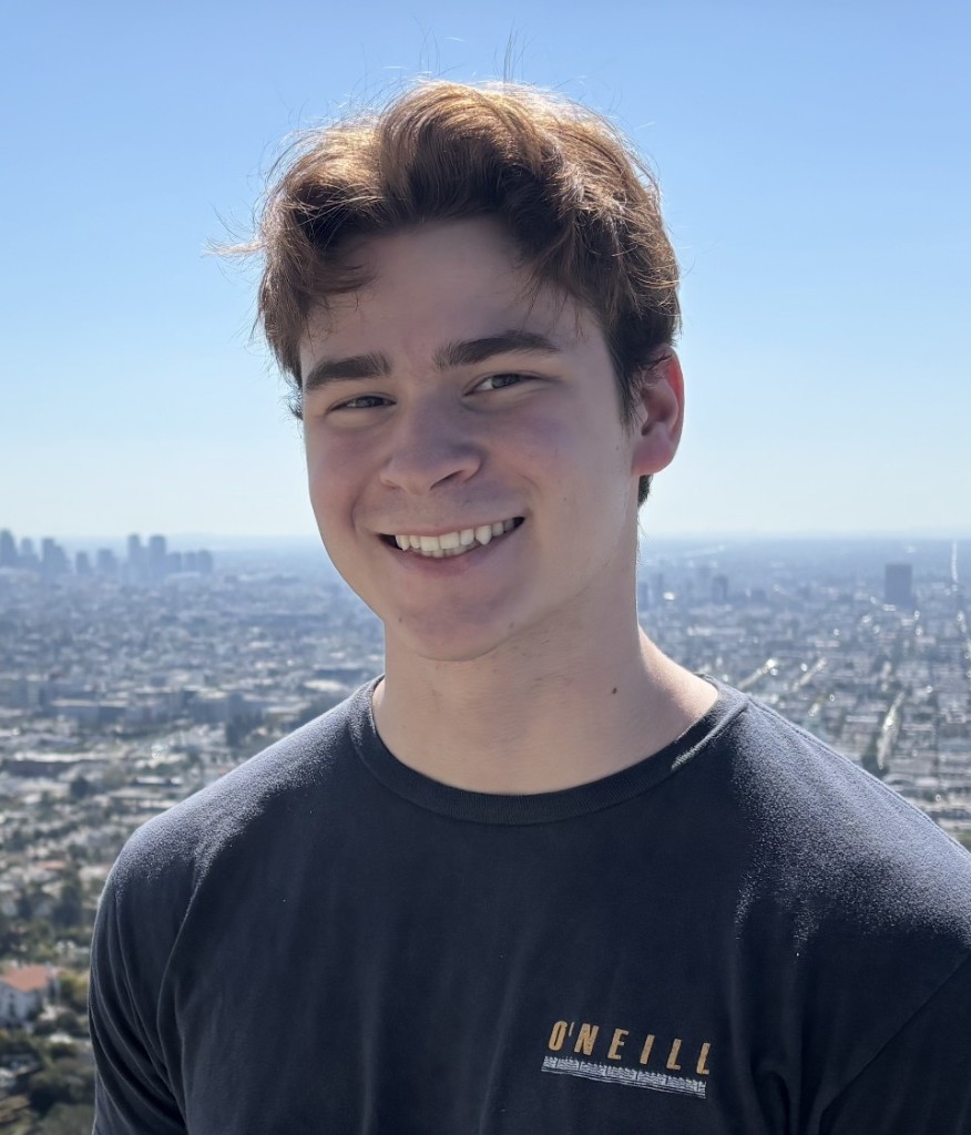 Portrait of Joseph Costa, HackBU Vice President of Event Planning, smiling outdoors above a sprawling city skyline.