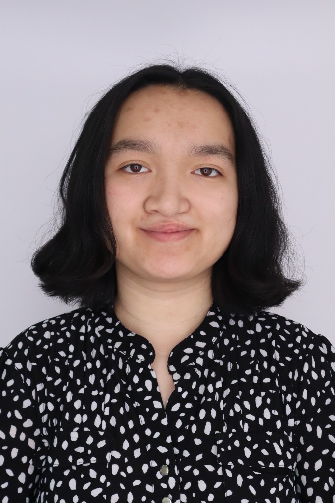 Portrait of Tianna Balkam, HackBU organizer, smiling against a plain backdrop in a black-and-white patterned blouse.