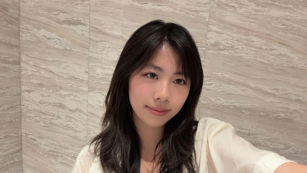 Portrait of Zuri Chan, HackBU organizer, smiling softly in a cream blouse against a marble wall.